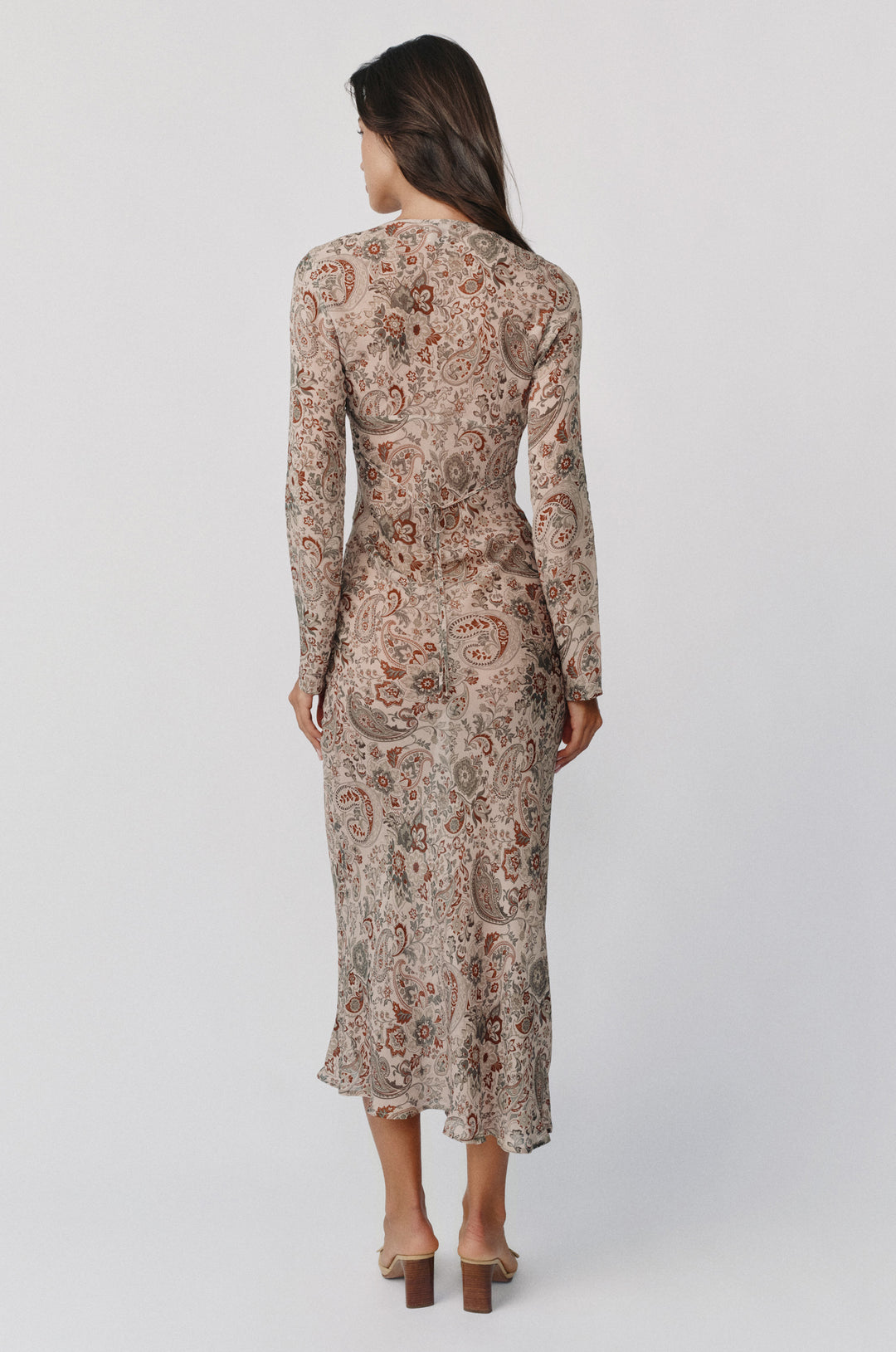 Back view of the Josephine long-sleeve midi dress in stone paisley print with a sheer finish and back tie detail.