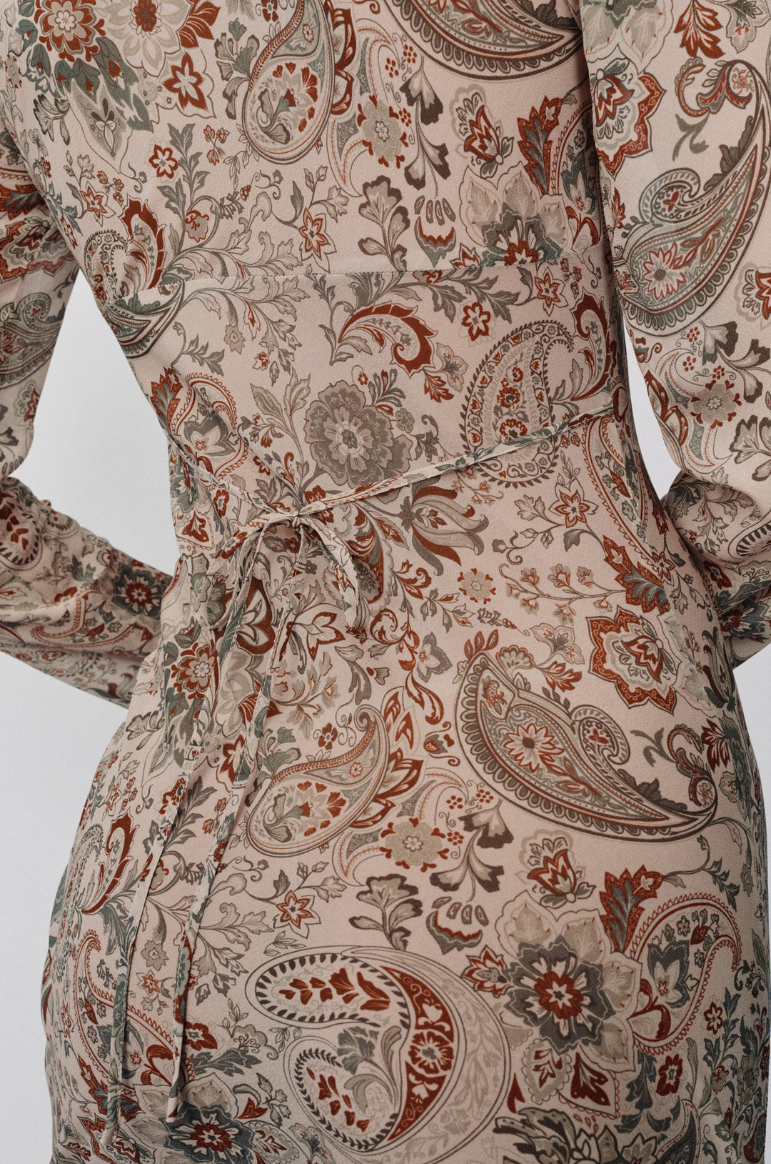 Josephine dress in stone paisley print with long sleeves and a delicate back tie detail in sheer fabric.