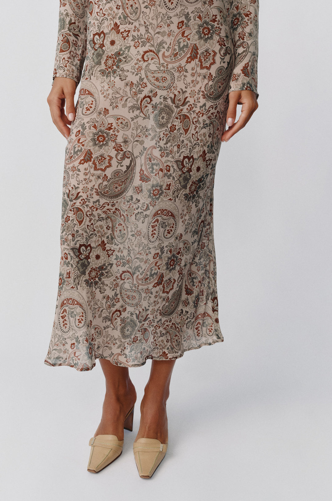 Josephine dress in stone paisley print with long sleeves and a sheer, flowing midi-length silhouette.