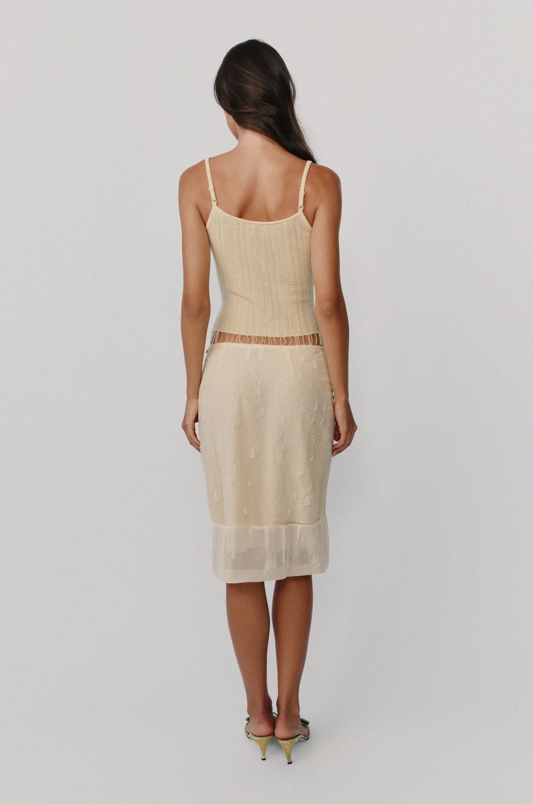 Champagne midi skirt with delicate vine embroidery, beaded detailing, and a sheer pleated hem worn with a matching tank top.