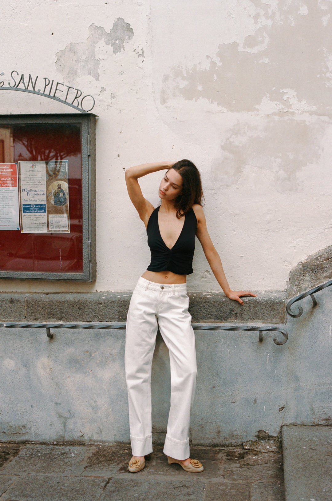 Woman in white Agnes low-rise selvedge denim jeans with fixed cuffed hem, paired with a black top.