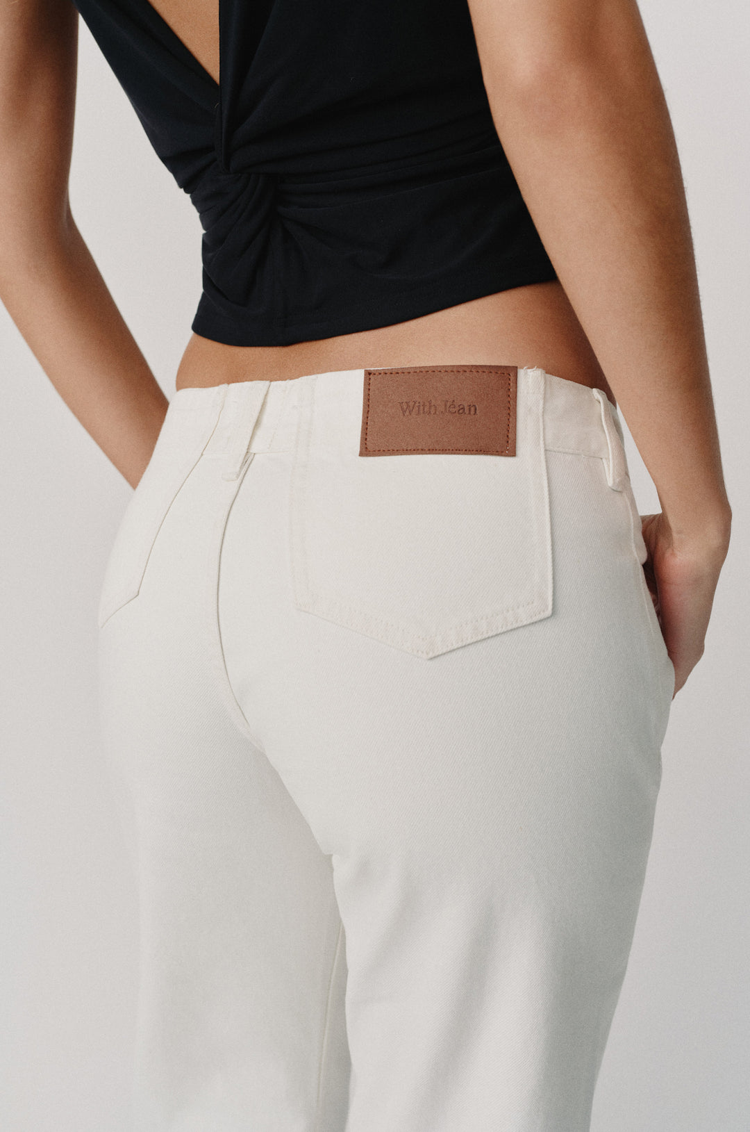 Agnes low-rise white selvedge denim jeans with a brown "With Jean" patch on the back.