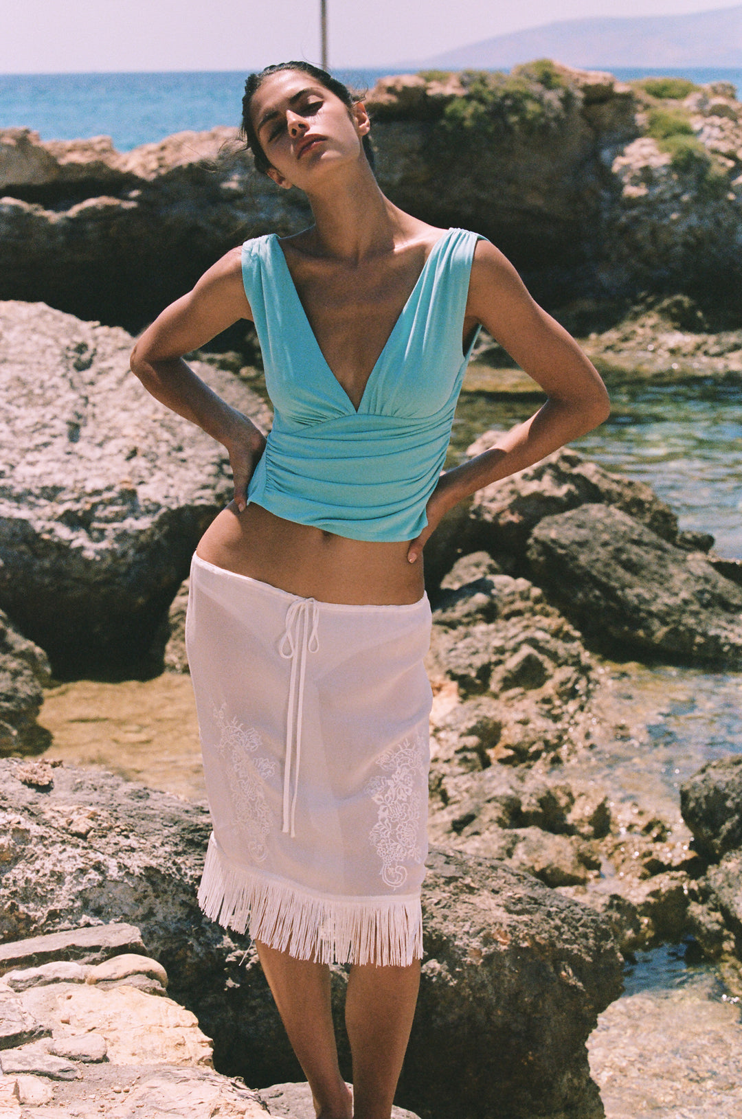 Low-rise white Andie skirt with an adjustable drawstring waist, delicate front embroidery, and a fringe hemline.