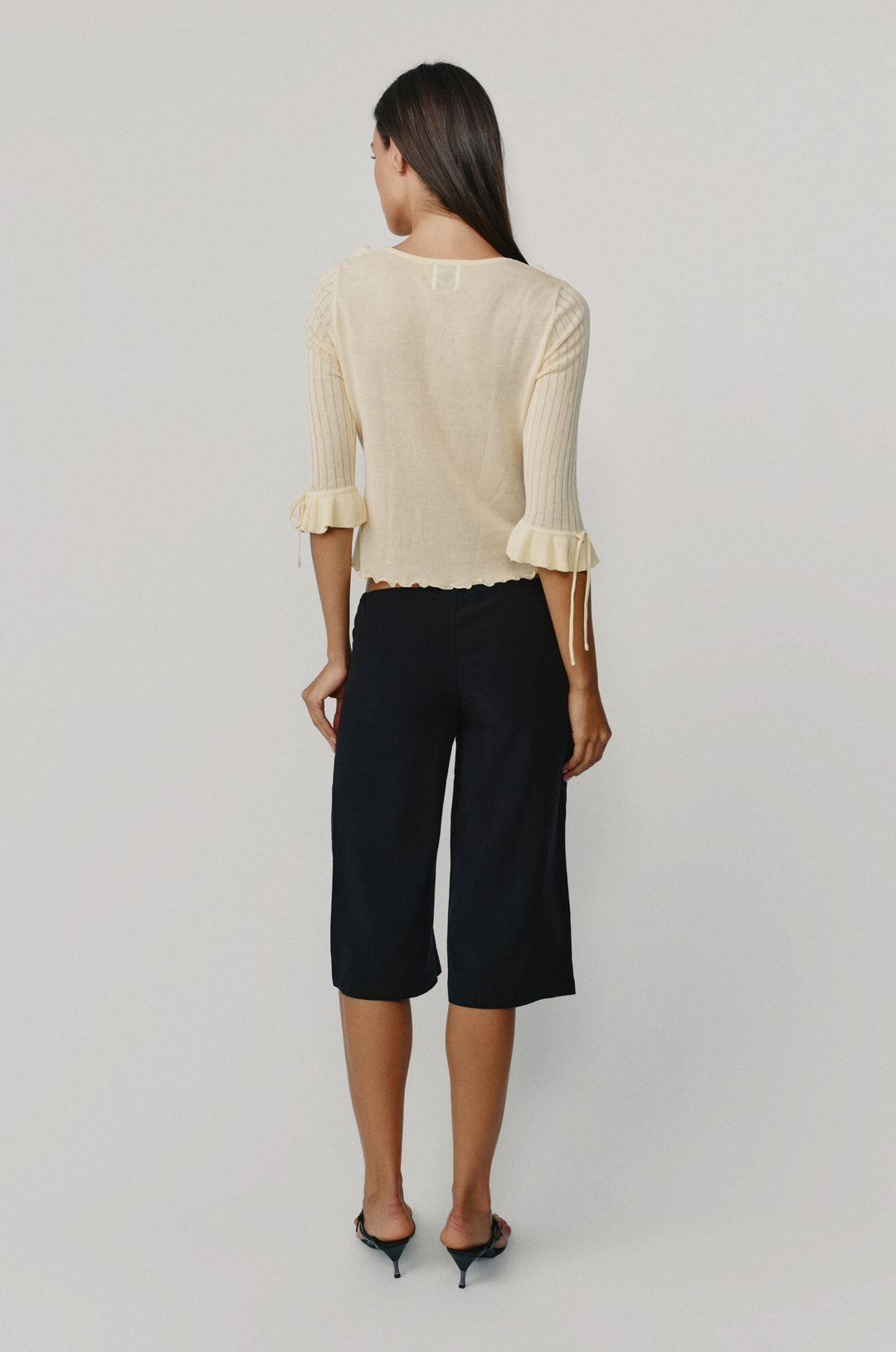Model wearing black Arden Capri pants with a relaxed fit and low-rise waist, paired with a cream ribbed top.