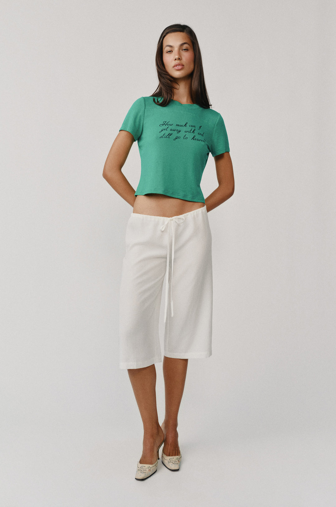 Woman in white Arden Capri Pant with adjustable tie waistband, paired with a green crop top.