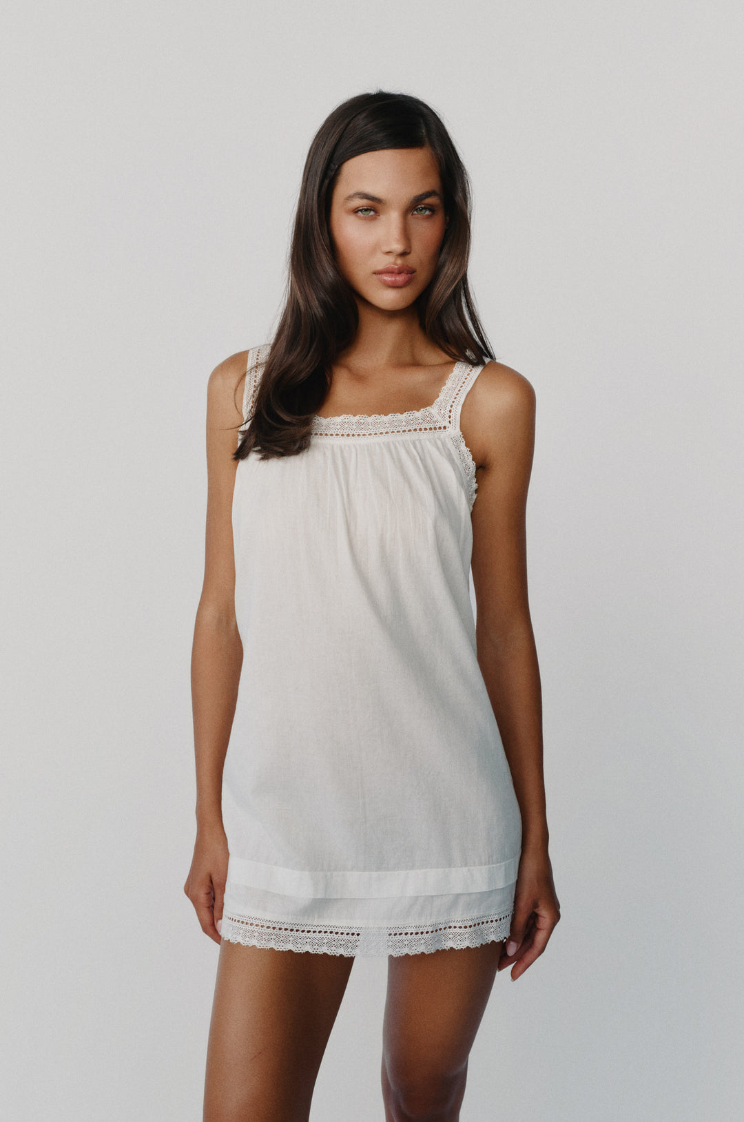 Arielle white cotton mini dress with a square neckline, delicate lace trim, and thin straps.