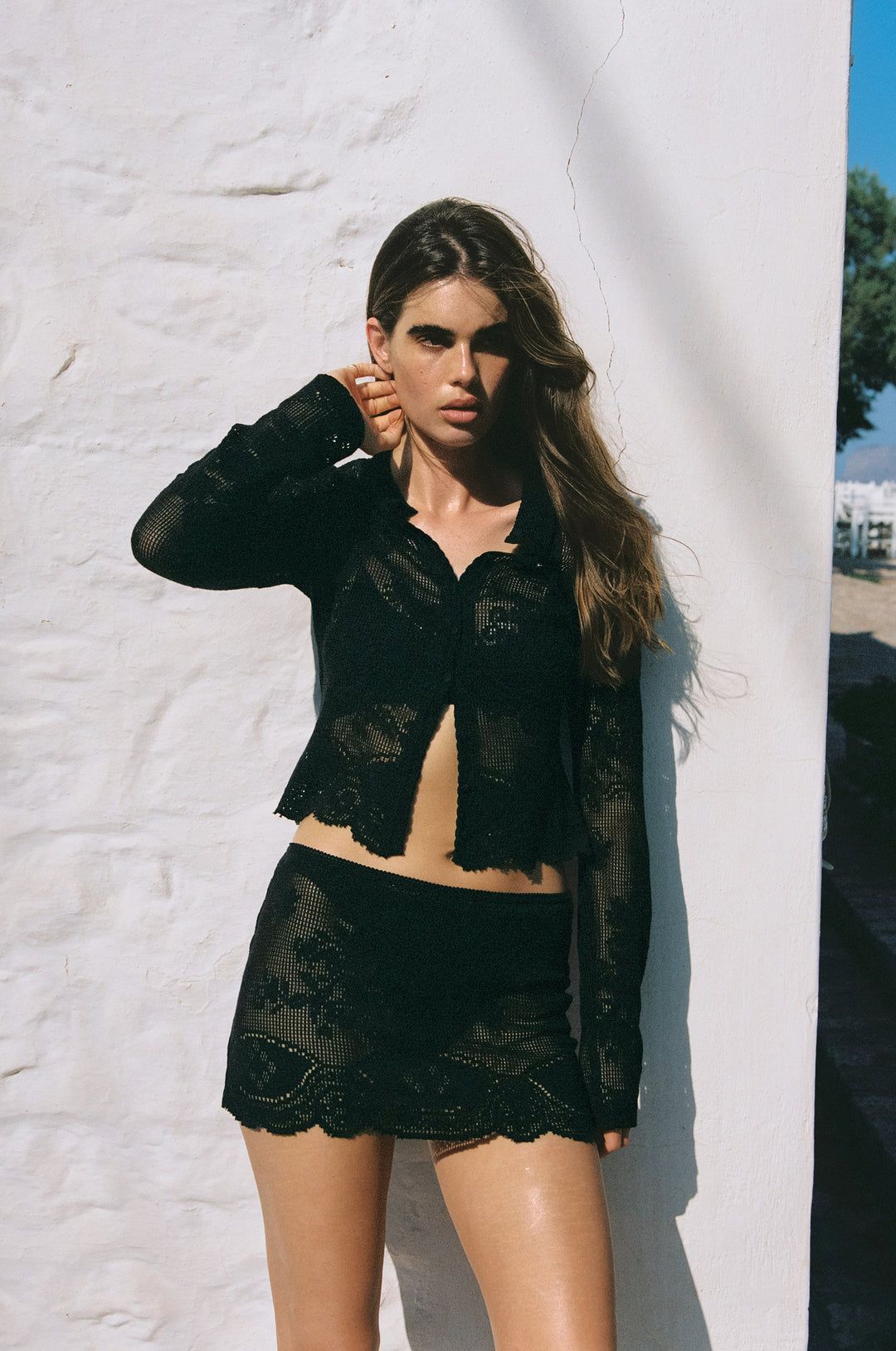 Black mini skirt featuring sheer hand-drawn crochet lace, an elasticated waistband, and a delicate scalloped hem.