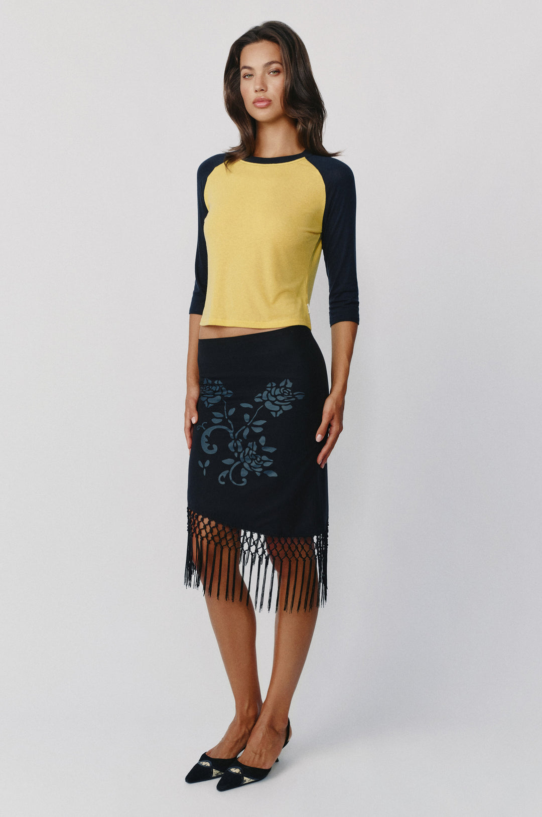 Billie raglan tee in yellow with midnight navy sleeves, paired with a black floral skirt featuring a fringed hem.