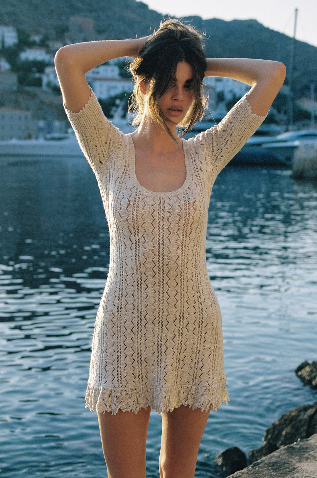 Pearl mini dress featuring an openwork knit design, ribbed scoop neckline, and textured hem by the water.
