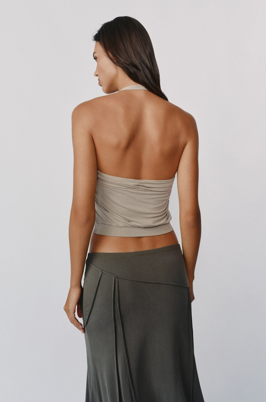 Stone-colored halter top with a ruched band and fitted hem, worn by a model against a neutral background.