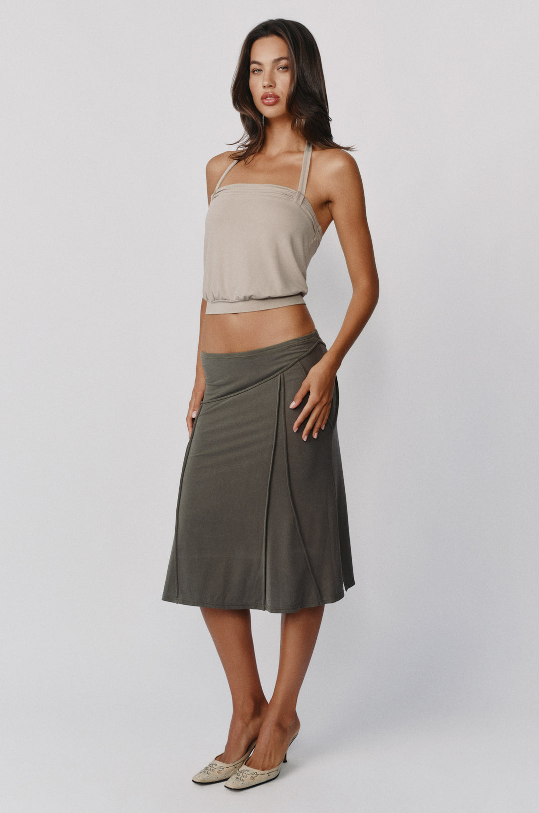 Stone-colored halter Briar Top with a ruched band and loop detailing, paired with a dark olive midi skirt.