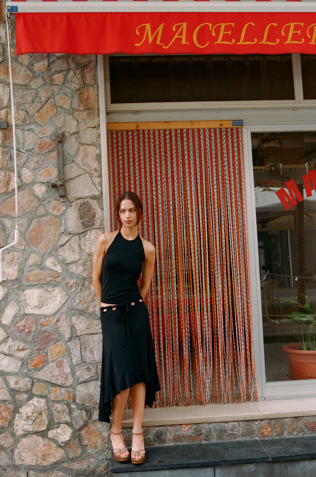 Black Carrie Skirt: low-rise midi with adjustable tie waistband, cut-out details, and ruffle hem.