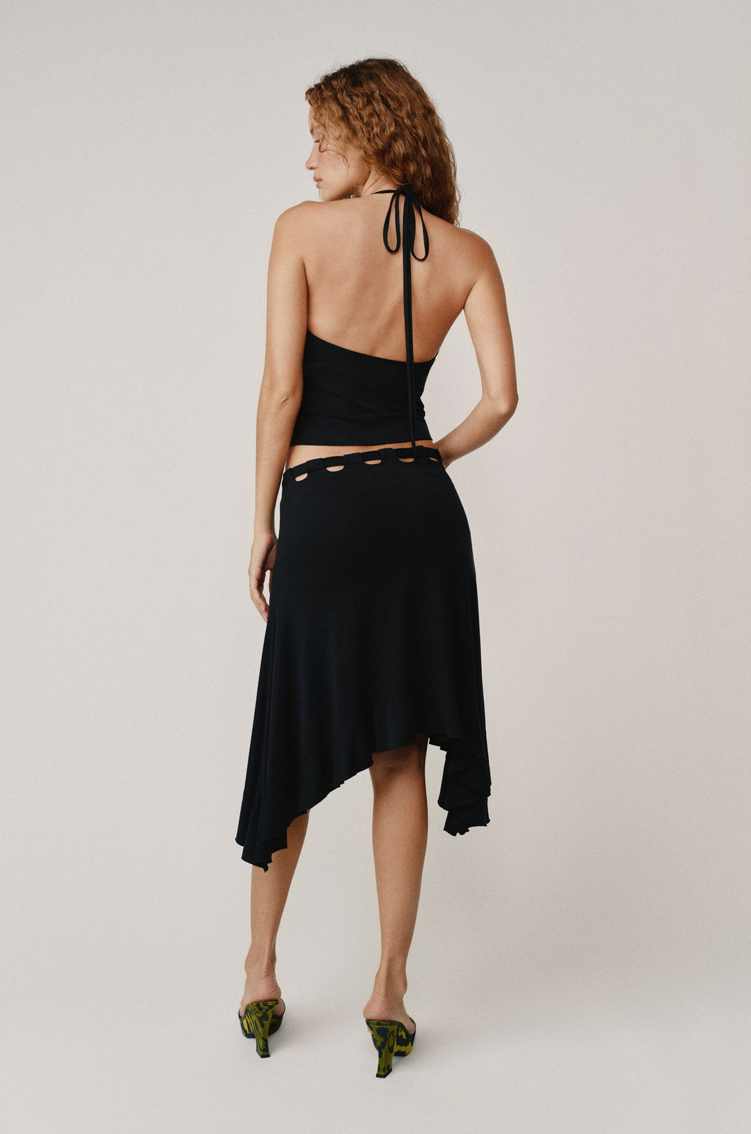 Black Carrie Skirt: low-rise midi with adjustable tie waistband, cut-outs, and ruffle hem.