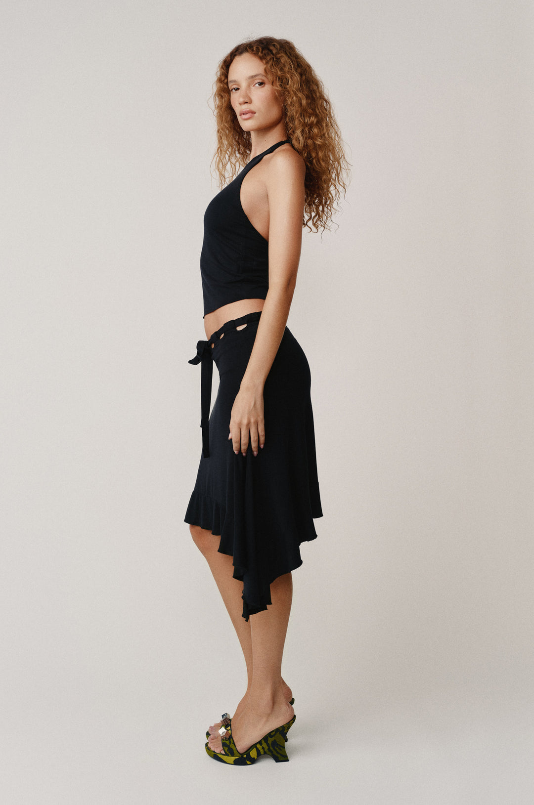 Black Carrie Top, a halter-style top with self-tie neck and low back, paired with a black skirt.