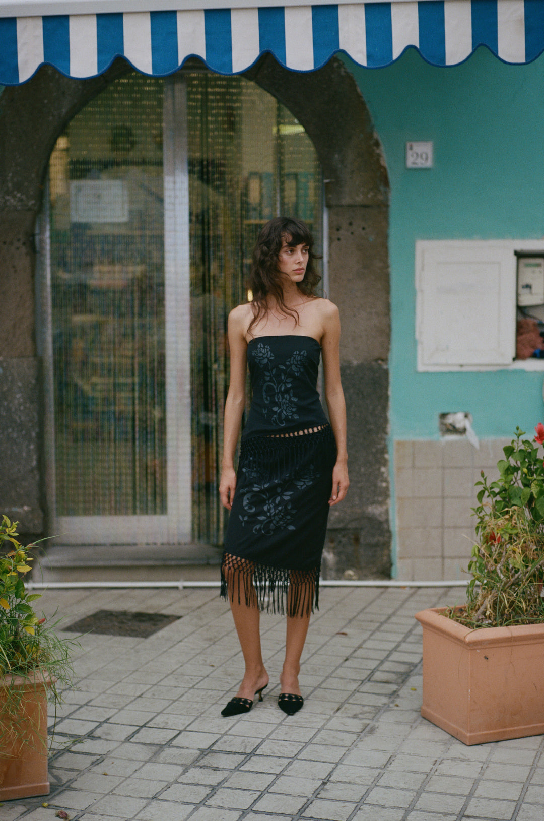 Black low-rise Daria skirt featuring a floral print, asymmetrical hemline, and decorative macrame fringe detailing.