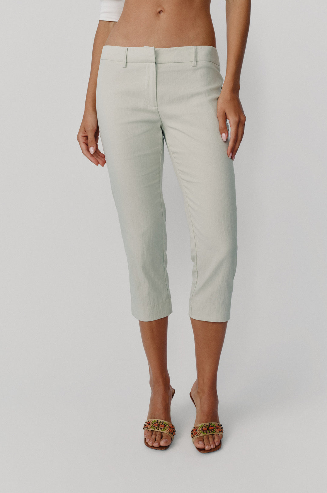 Low-rise dusty sage Davis capri pants with a slim fit, front zip closure, and belt loops.