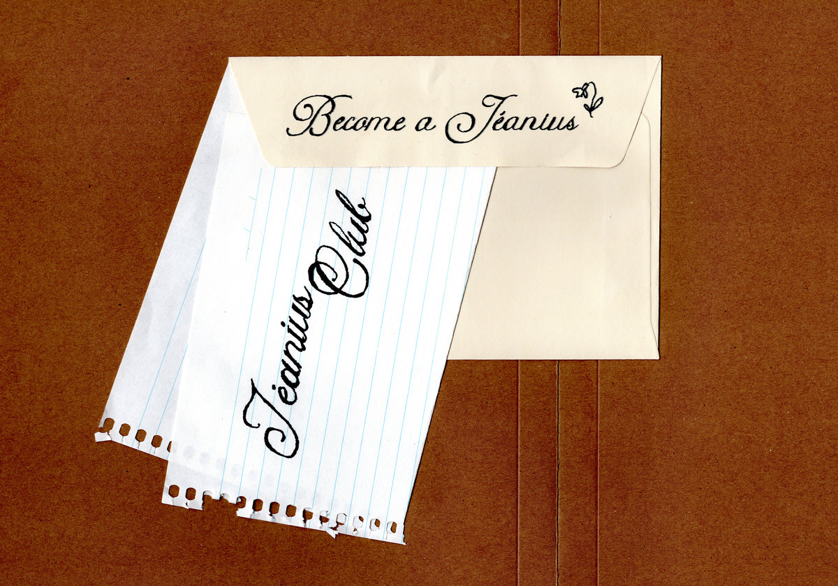 A flat-lay arrangement of vintage-style paper ephemera and stationery items on a brown textured background, including a lined notepad, cream cards with black script text reading 'Jeanius Club' and 'Become a Jeanius', a white lace doily, and a clear plastic sleeve.