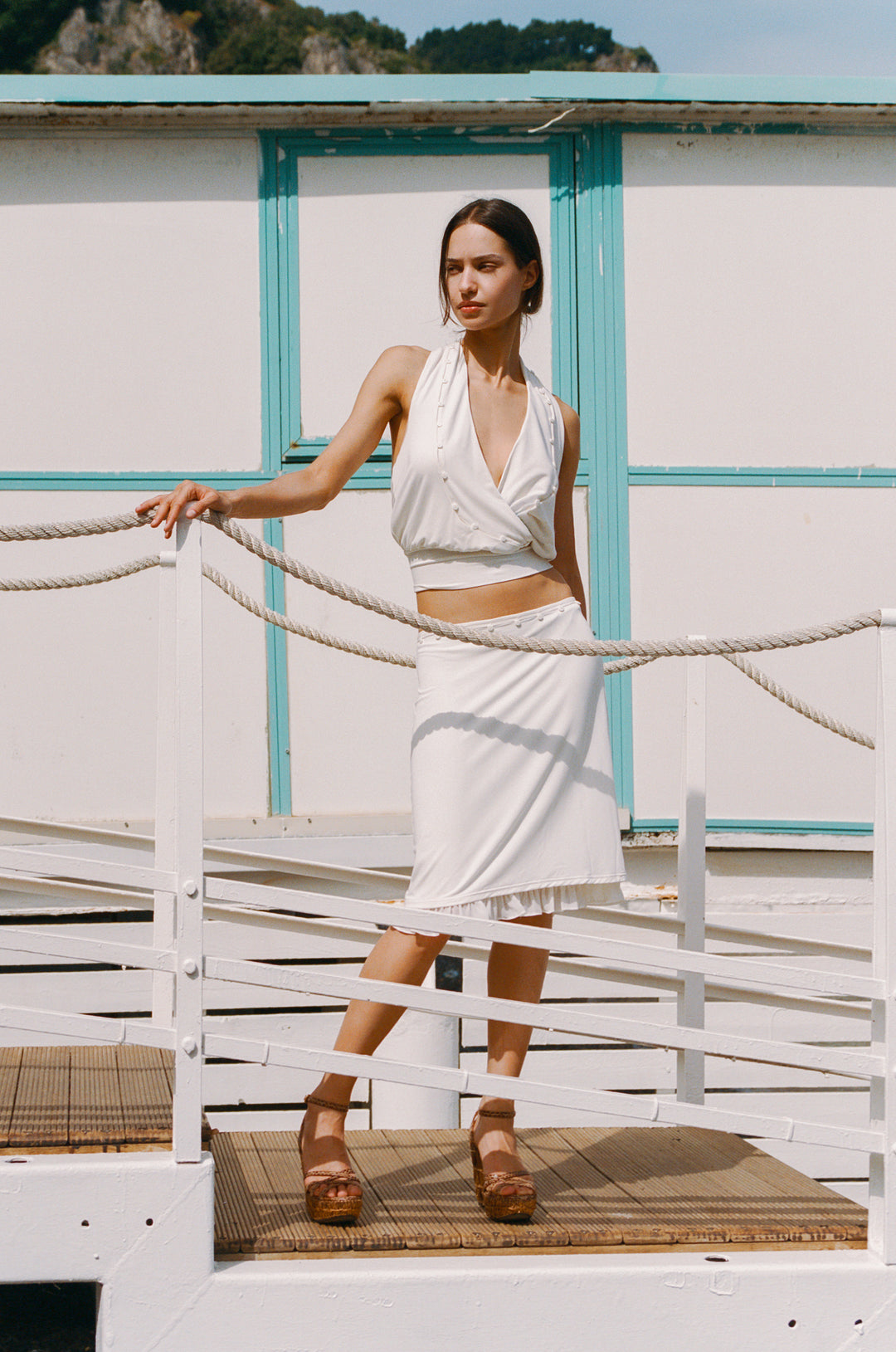 Model in an off-white Ella Skirt, a low-rise midi with button detailing and a frill hem.
