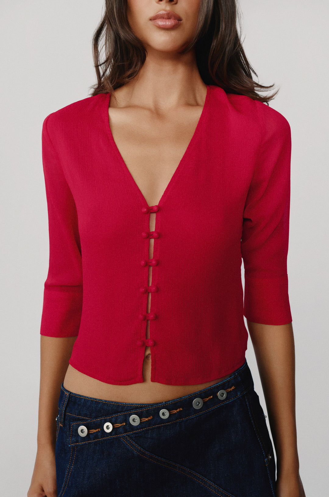 Red V-neck Elsie blouse with loop button-front closure and 3/4 length sleeves, worn with dark denim jeans.