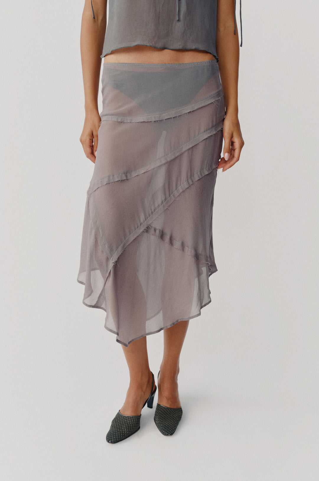 Dusty slate sheer low-rise skirt with frayed-edge panel detailing and an asymmetrical hem.