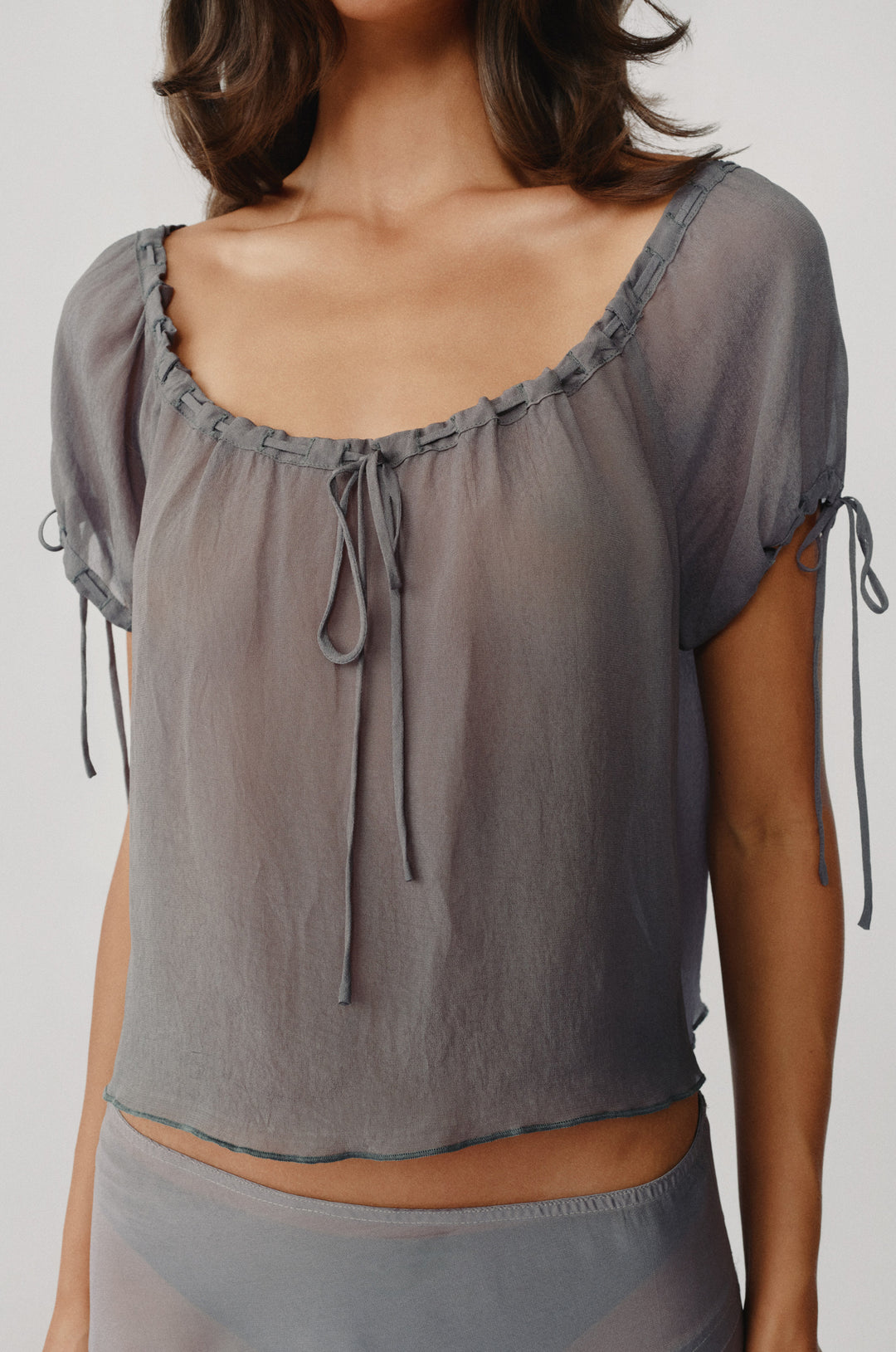 Sheer ash slate Gia top with a relaxed fit, adjustable tie neckline, and functional tie-detail short sleeves.