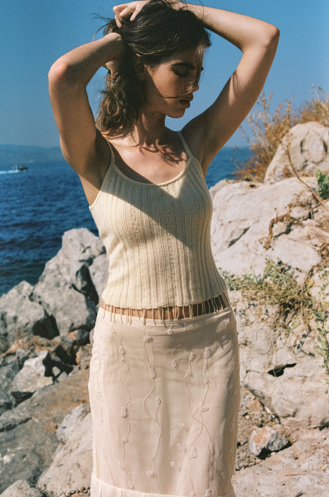 Pale yellow fine wool-knit Kayla top with delicate beaded embellishments and a beaded fringe hem worn outdoors.