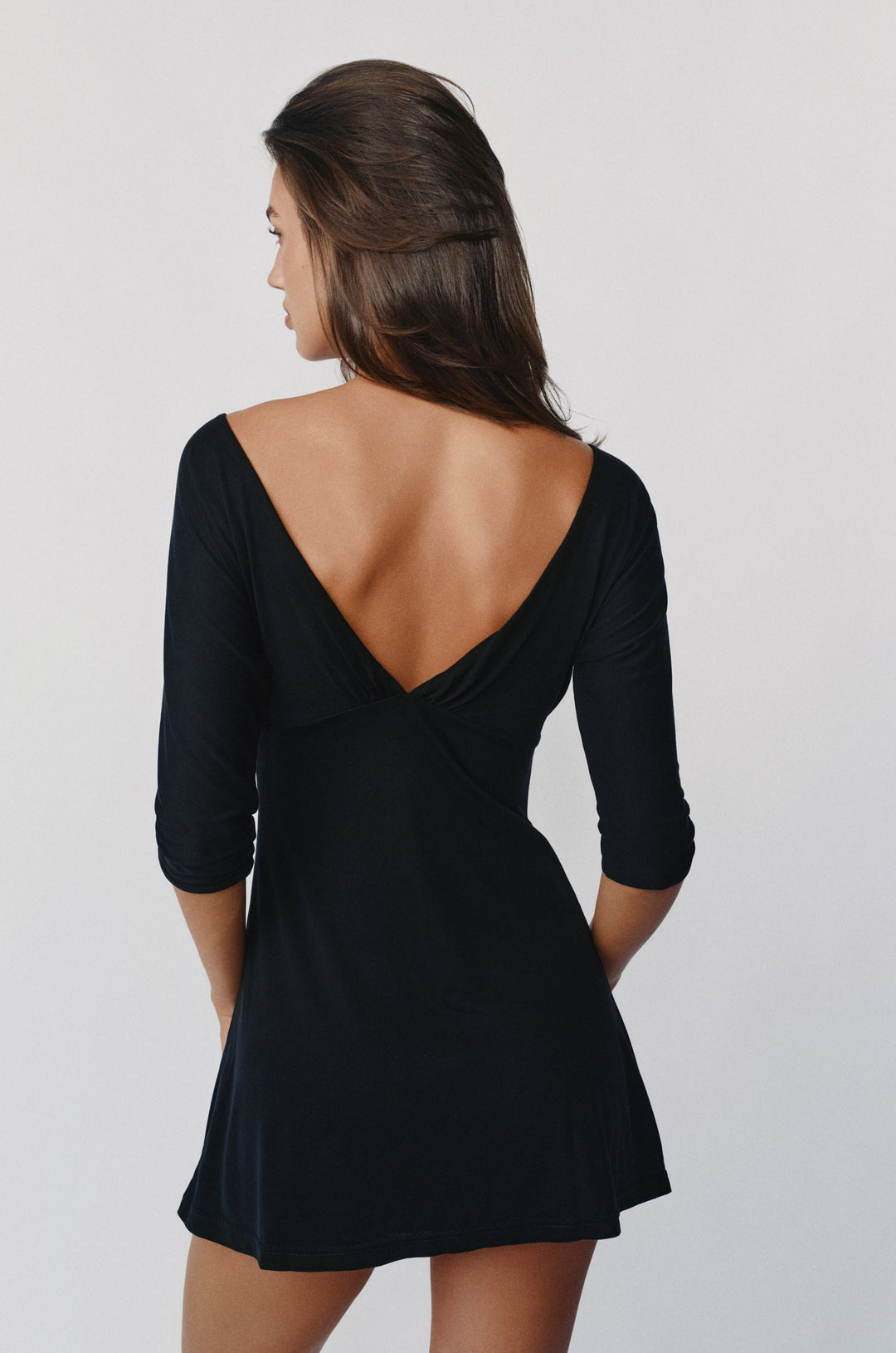 Black mini Lana dress with half sleeves and a deep V-back neckline, shown from behind on a model.