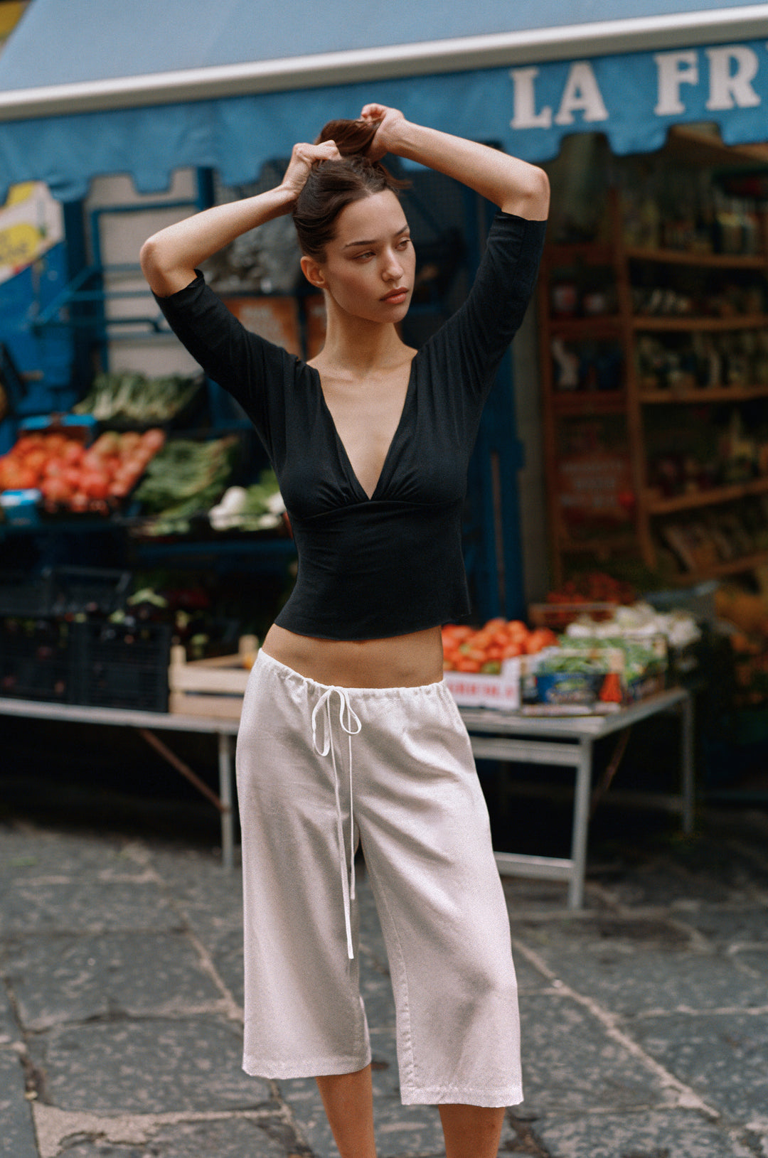 Black Lana Top with V-neck, half sleeves, gathered bust, and raw edge hems, worn by a model.