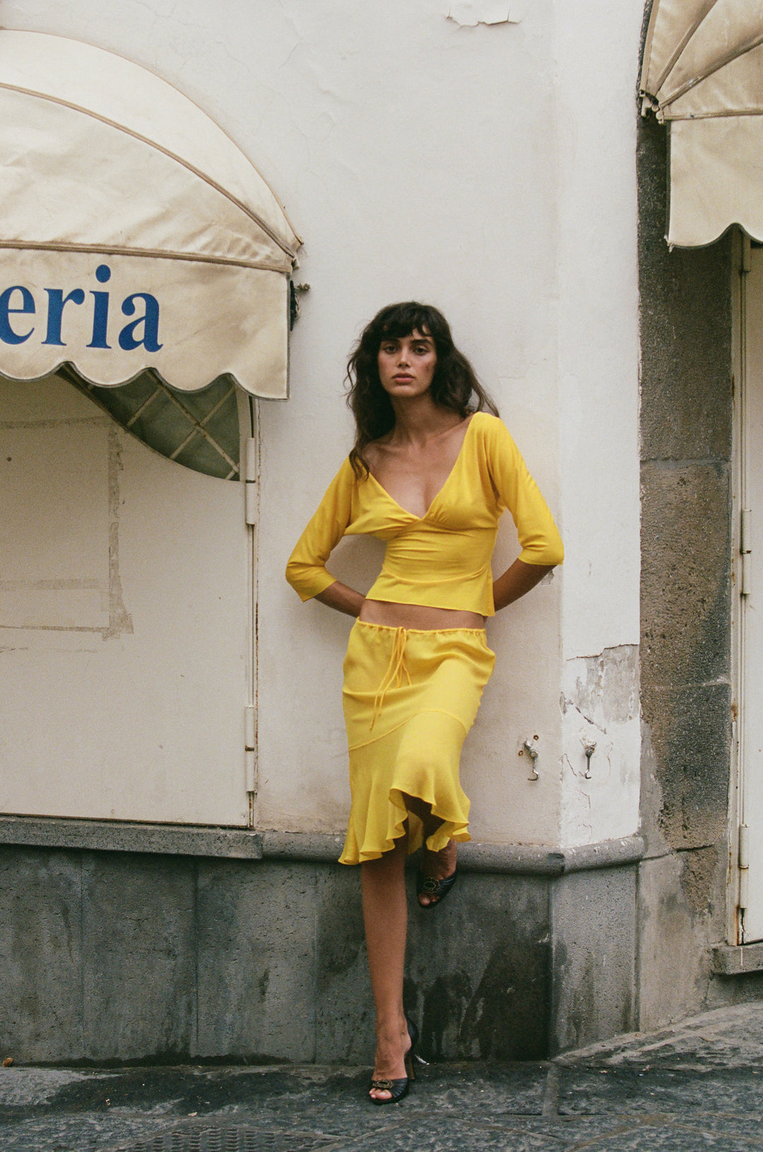Golden yellow slim-fit V-neck top with half sleeves and gathered bust detail, worn with a matching yellow skirt.
