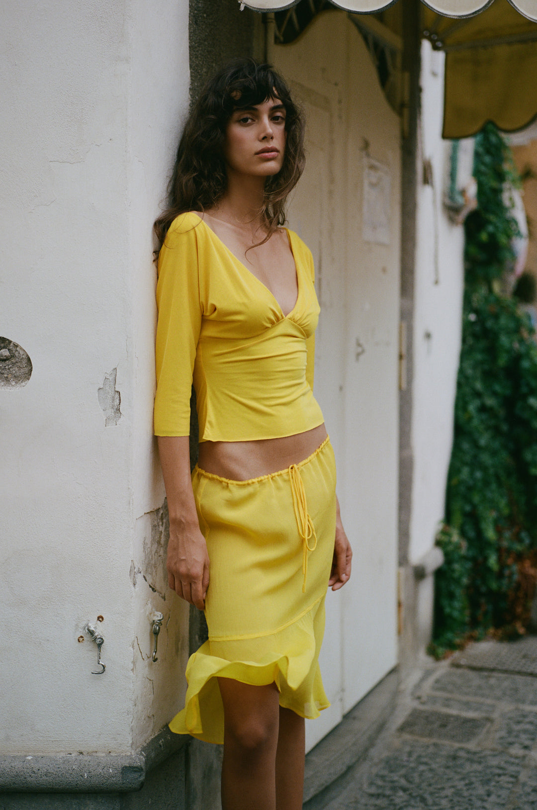 Golden yellow Lana top with V-neckline, half sleeves, and gathered bust detail, styled with a matching yellow skirt.