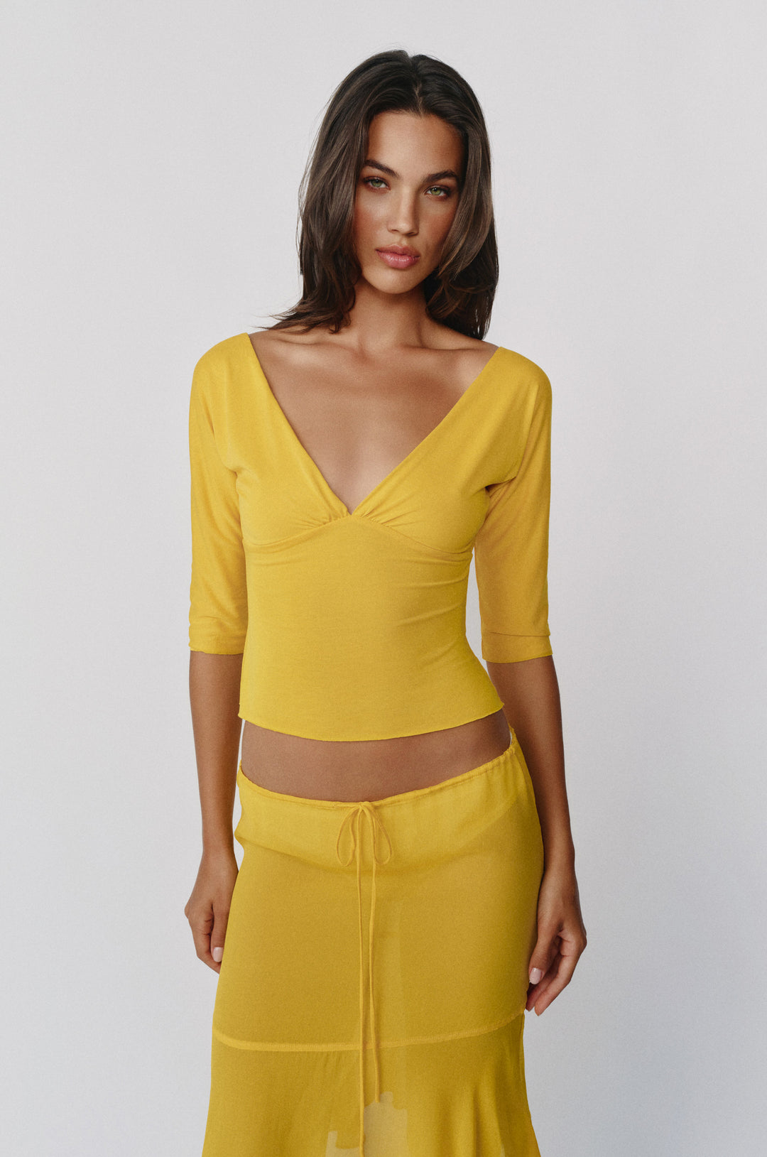 Golden yellow slim-fit Lana top with a V-neckline, half sleeves, and gathered bust detailing on a model.