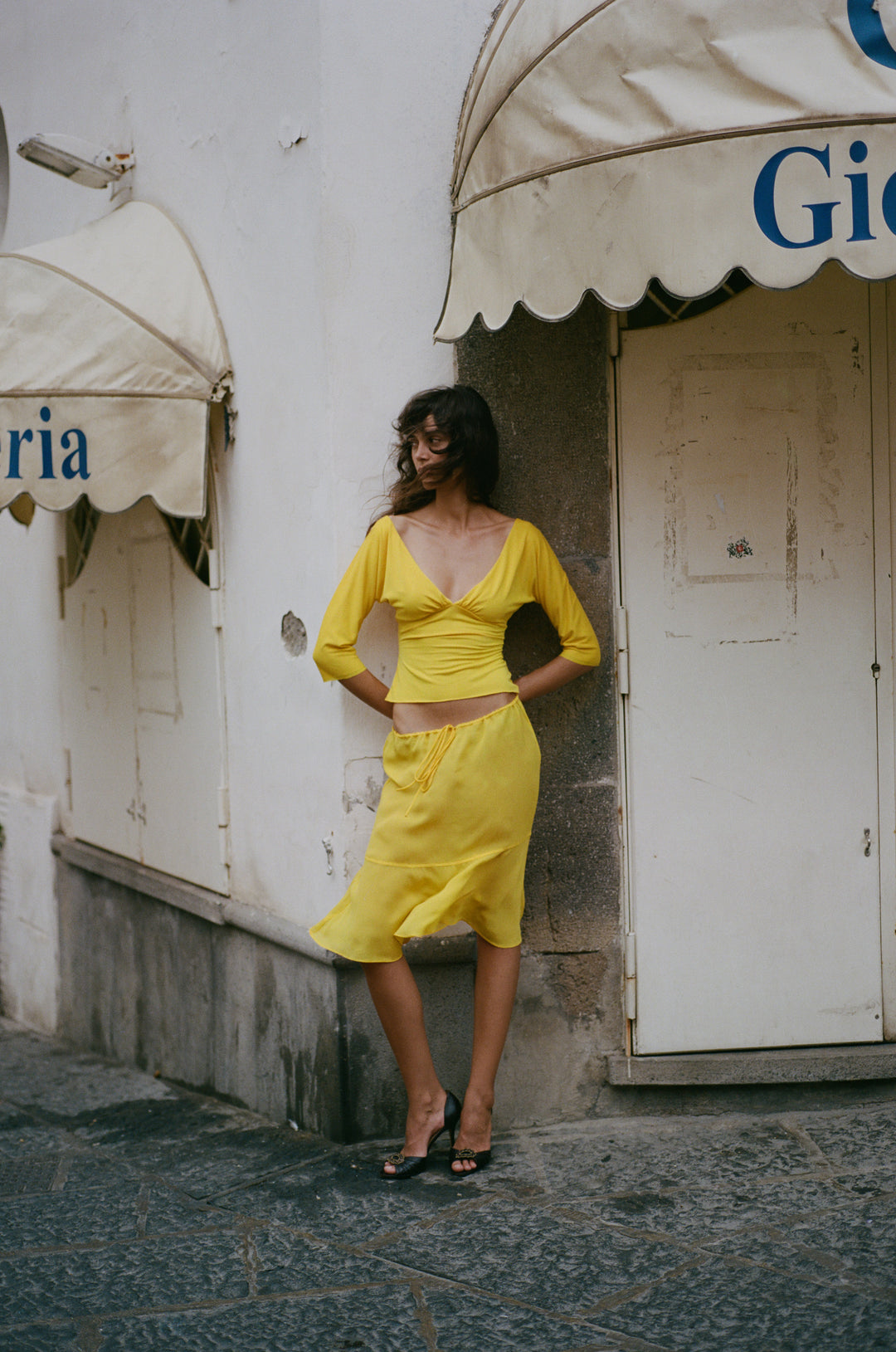 Golden yellow slim-fit Lana top with a V-neckline, half sleeves, and gathered bust detailing, worn with a matching skirt.