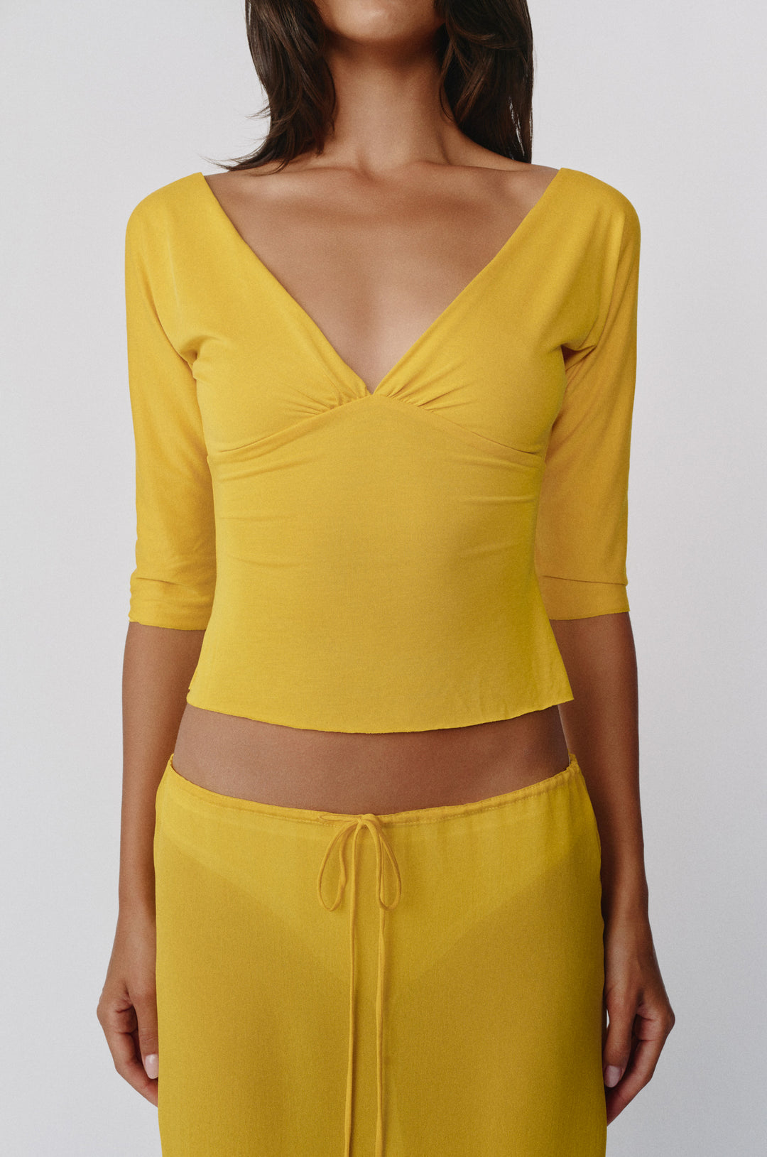 Slim fit golden yellow Lana top with a V-neckline, half sleeves, and gathered bust detailing on a model.