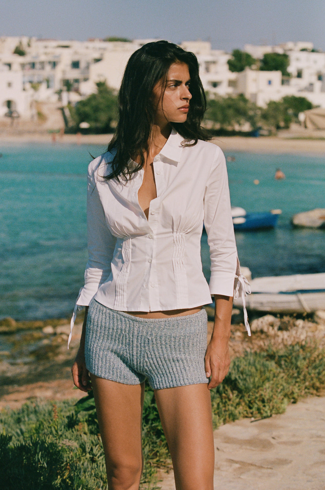 Fitted white button-down shirt with pintuck waist, collared neckline, and 3/4 sleeves with split tie cuffs.