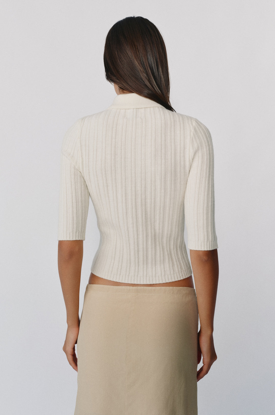 Back view of a ribbed off-white fine wool-knit top with a high neckline and half sleeves.