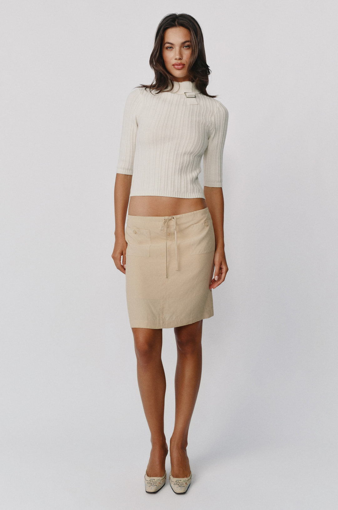 Off-white fine wool-knit Lula top with a high neckline, adjustable buckle detail, and half sleeves.