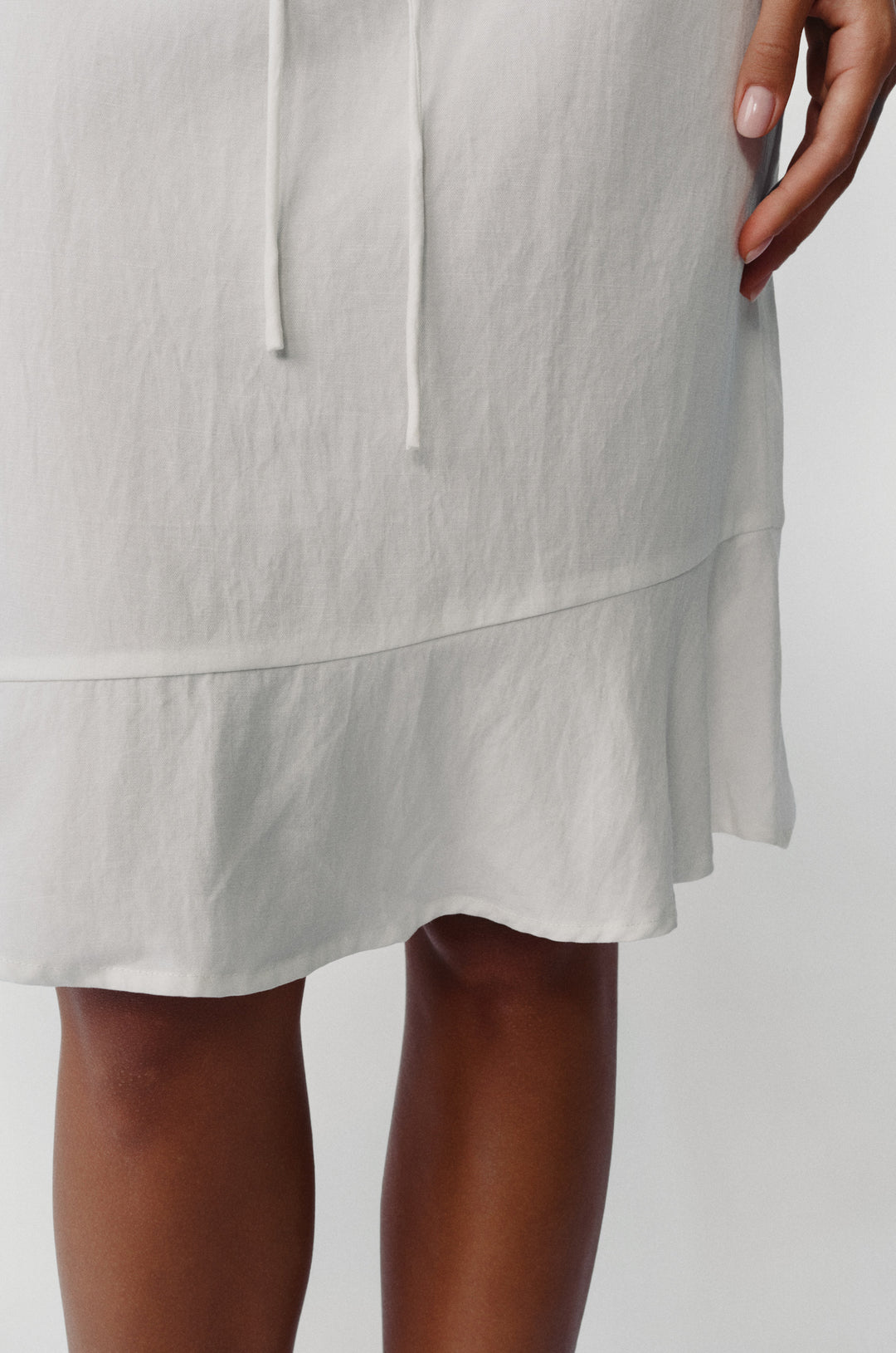 White low-rise Maisie skirt featuring an adjustable drawstring waist and asymmetrical ruffle hem detail.