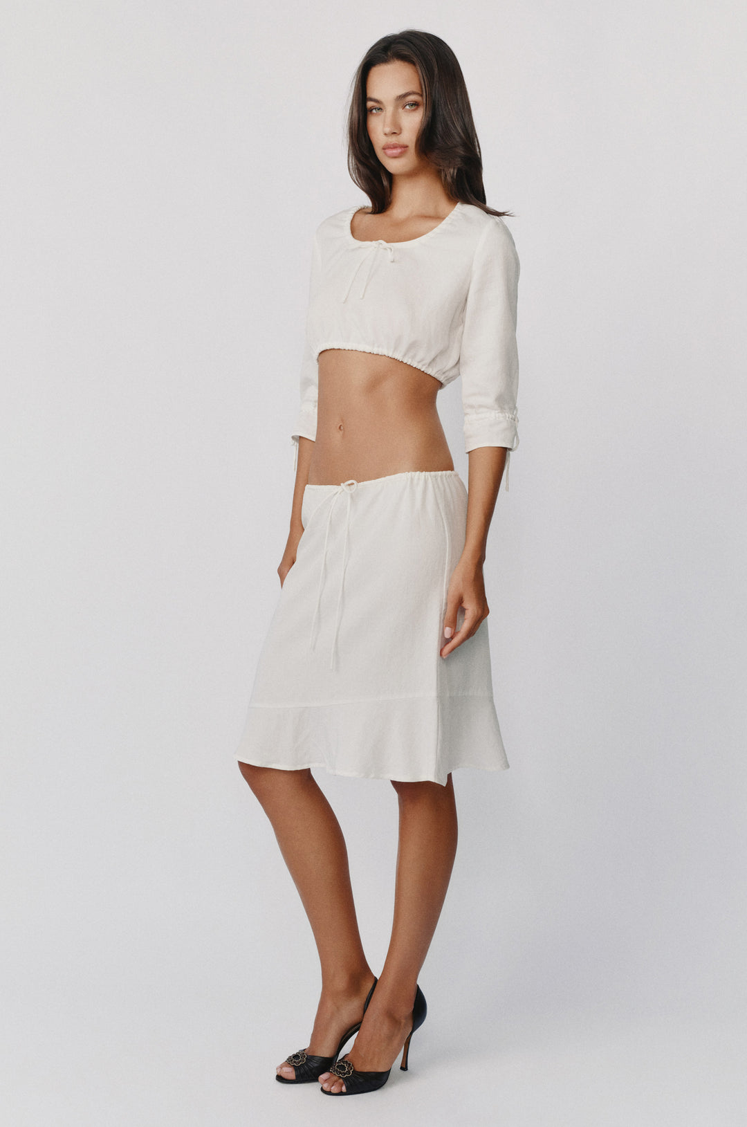 White low-rise Maisie skirt with an adjustable drawstring waist and asymmetrical ruffle hem detail.