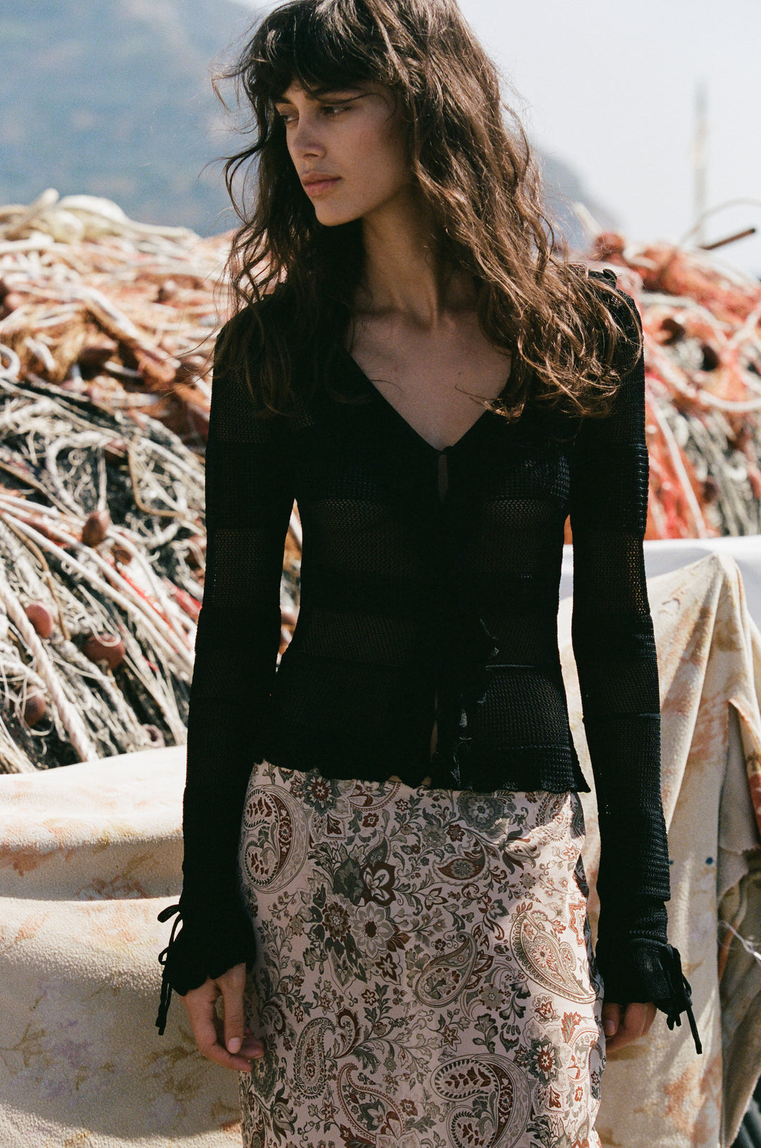 Black knitted long-sleeve top with a button-front neckline, ruffle trim, and tie-detail cuffs.