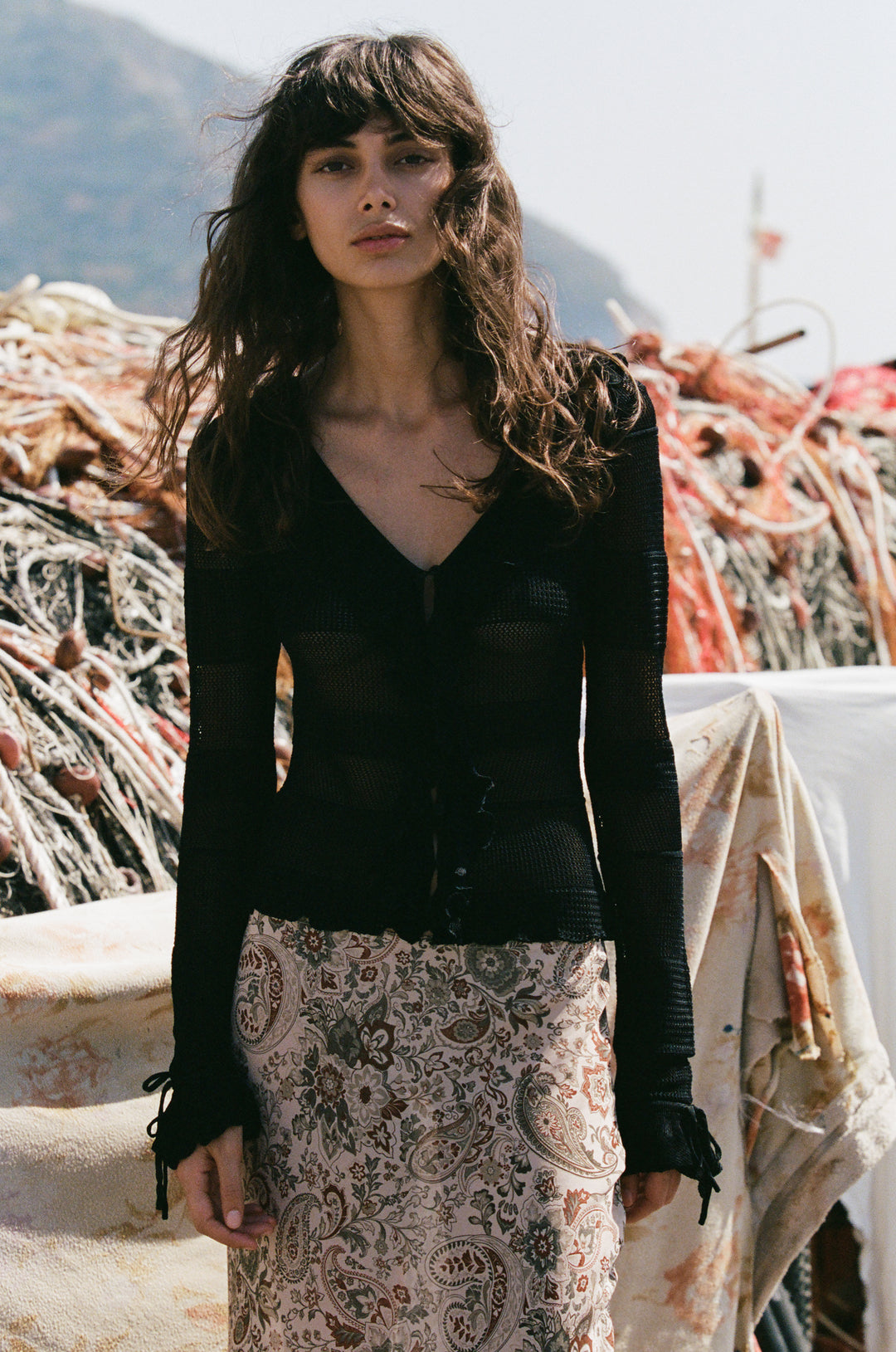 Black knitted long-sleeve top with a button-front neckline, ruffle trim, and tie-detail cuffs.