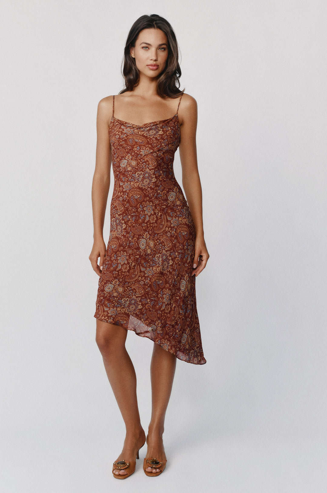 Mallory dress in terra paisley print featuring a cowl neck, spaghetti straps, and an asymmetrical hemline.