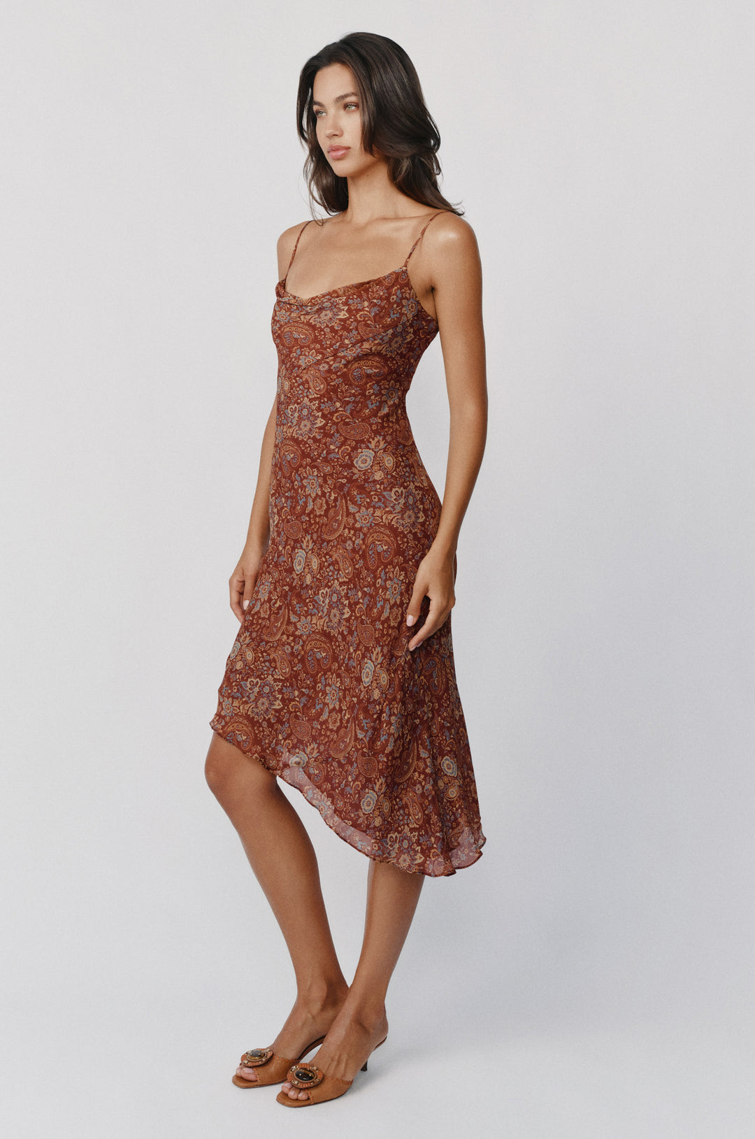 Mallory terra paisley dress with a cowl neck, spaghetti straps, and an asymmetrical hemline on a model.