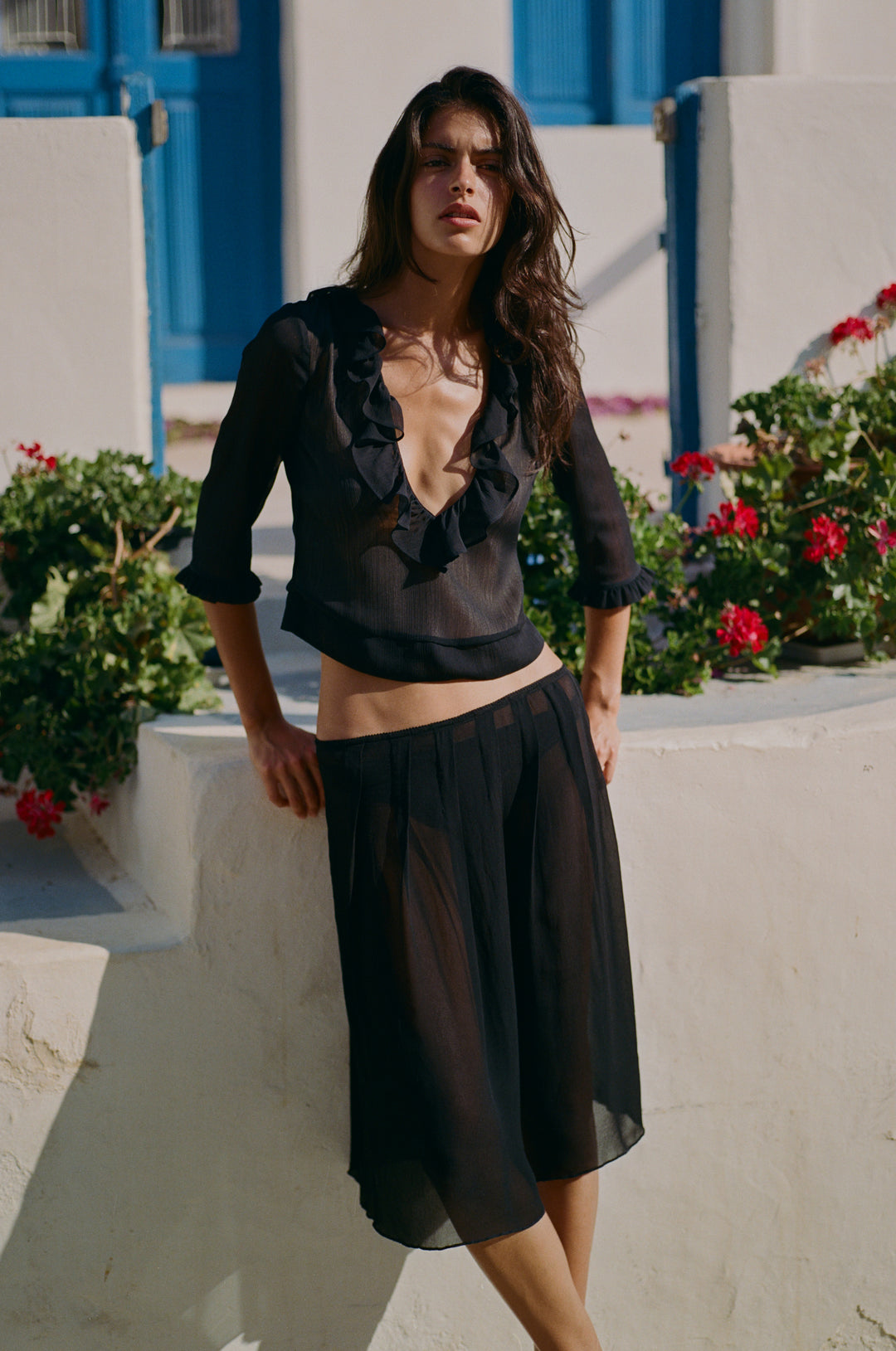Black Nadia blouse featuring a deep V-neckline, ruffle trim, and 3/4 sleeves, worn with a matching sheer black skirt.