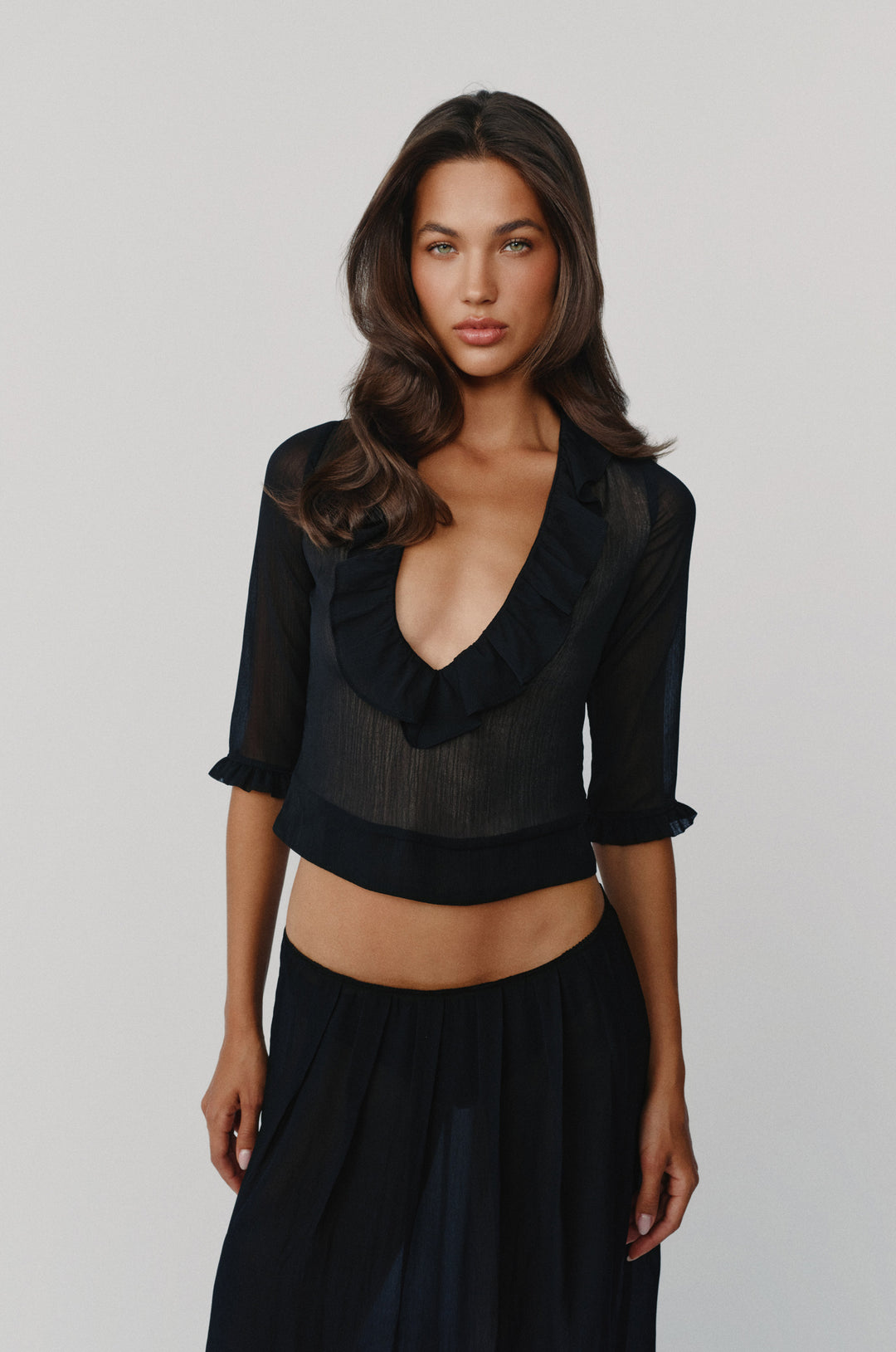 Black Nadia blouse with a deep V-neck, ruffle-trim collar, and 3/4 length sleeves with ruffled cuffs.