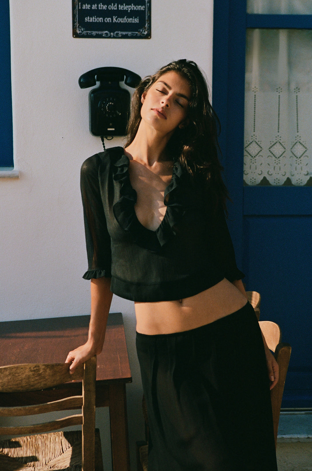 Black Nadia ruffle-trim blouse with a deep V-neckline and 3/4 length sleeves worn by a woman outdoors.