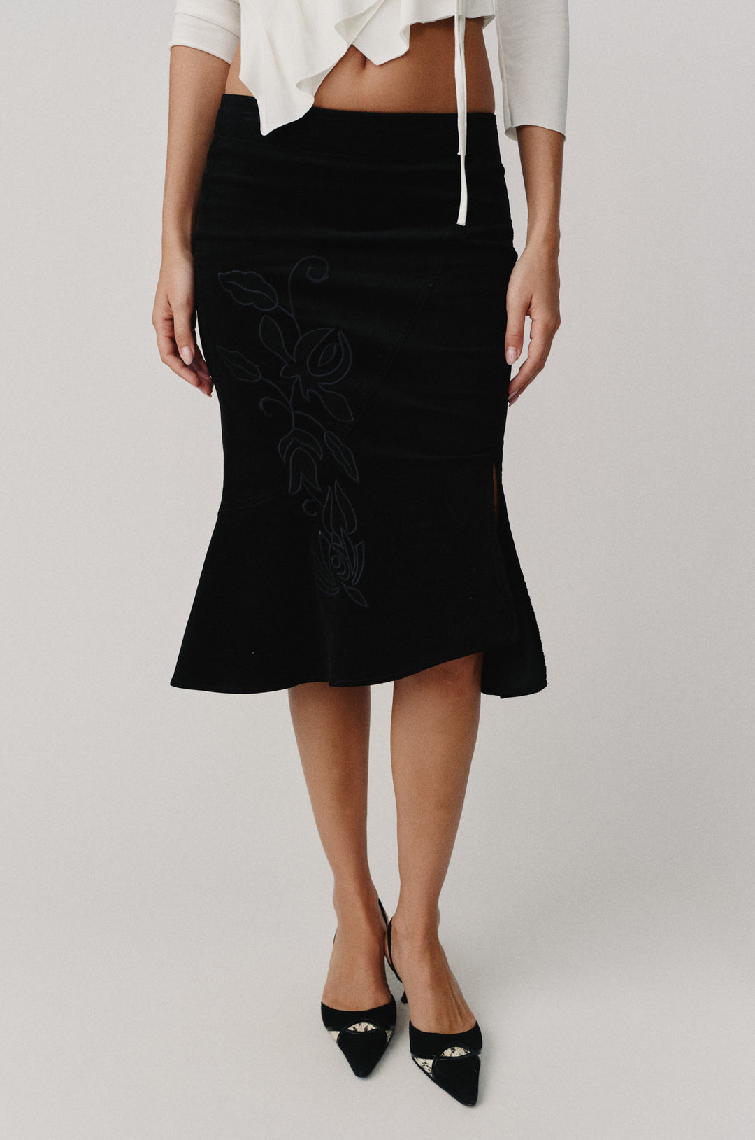 Black Naomi midi skirt with custom embroidered floral applique and subtle front slit.