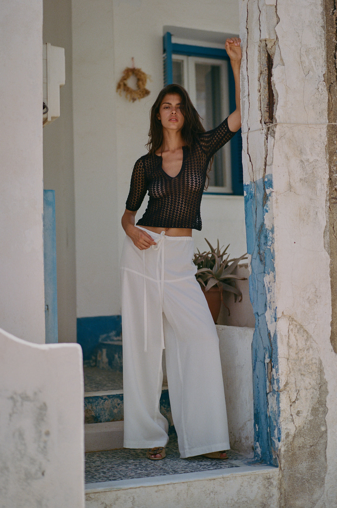 Loose-fit white Norah pants with an adjustable self-tie waistband, styled with a black crochet top.