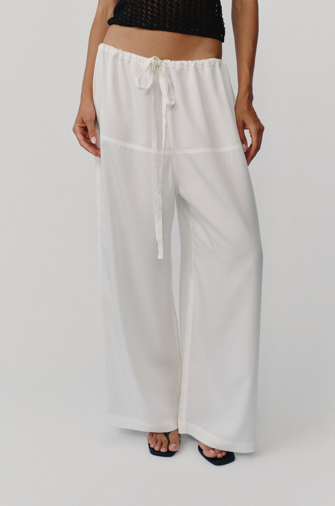 Loose-fit white Norah pants featuring a high waistband with an adjustable self-fabric tie and wide-leg silhouette.
