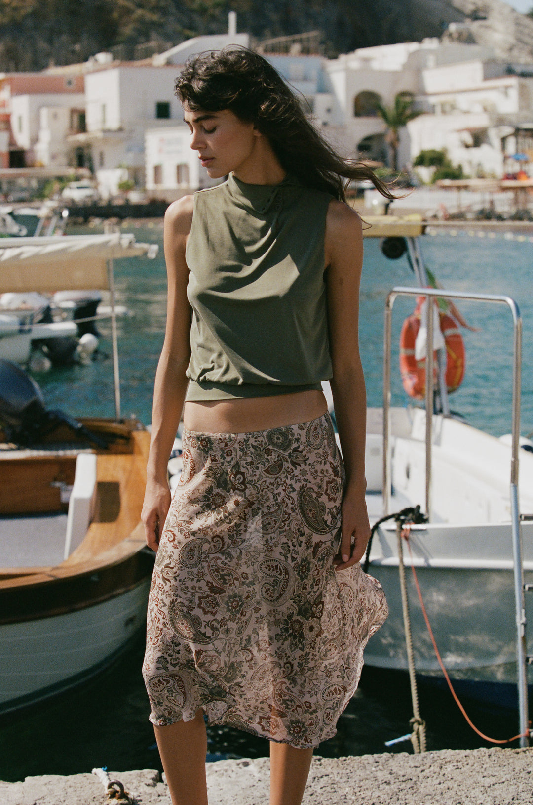 Olea skirt in stone paisley print featuring a sheer, flowy fabric worn low on the hips by a harbor.
