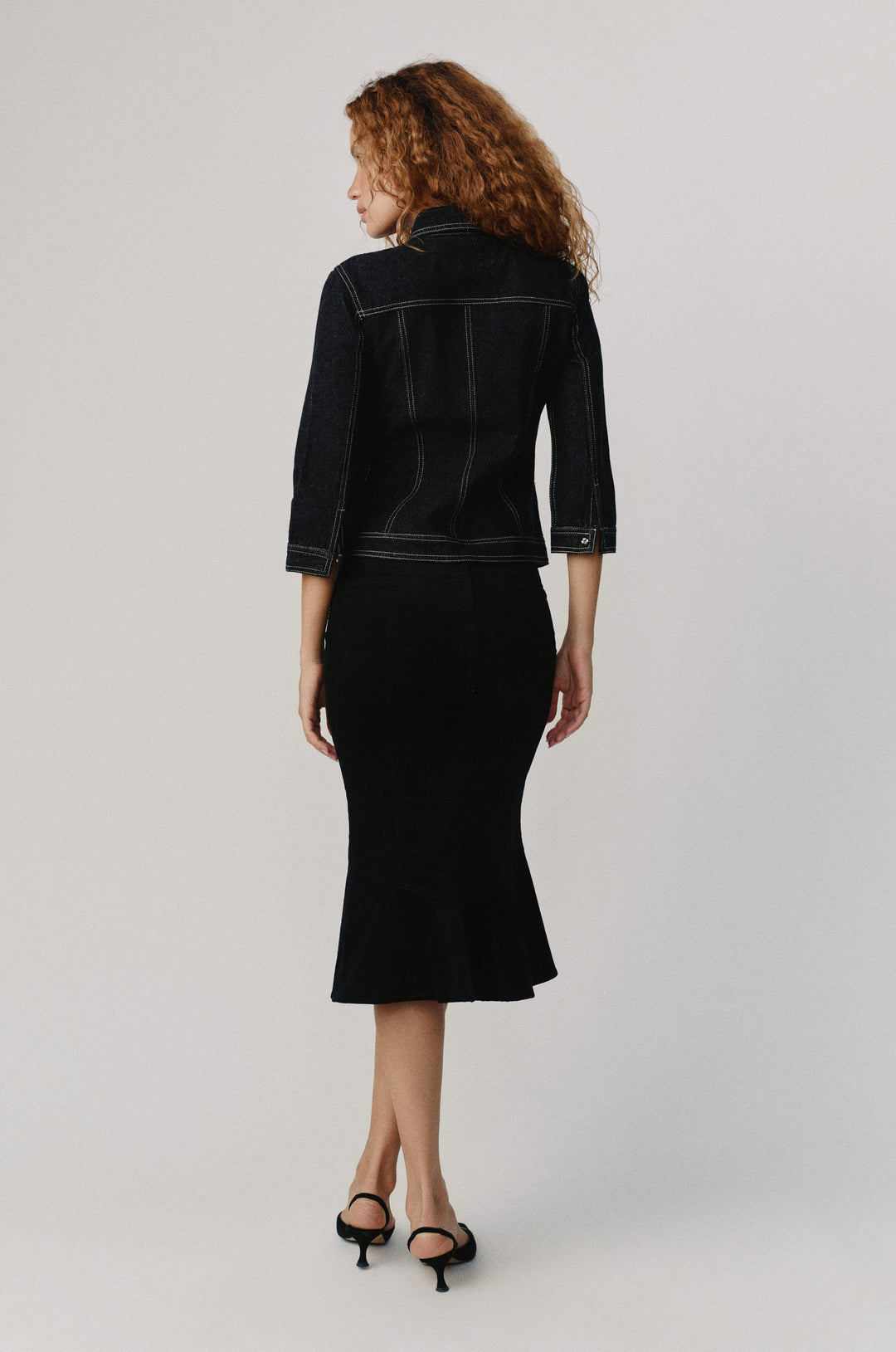 Olivia Jacket in indigo denim, featuring 3/4 sleeves and contrast stitching, worn with a black skirt.